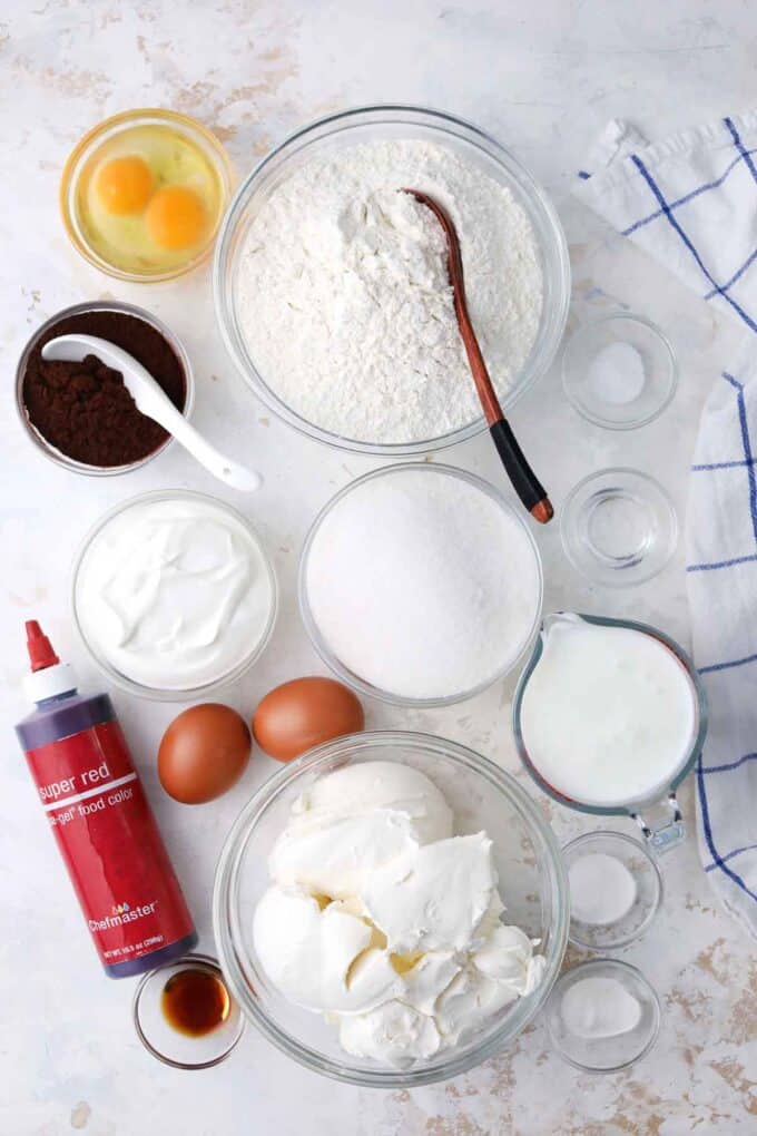 red velvet cheesecake cake ingredients in bowls on a white surface