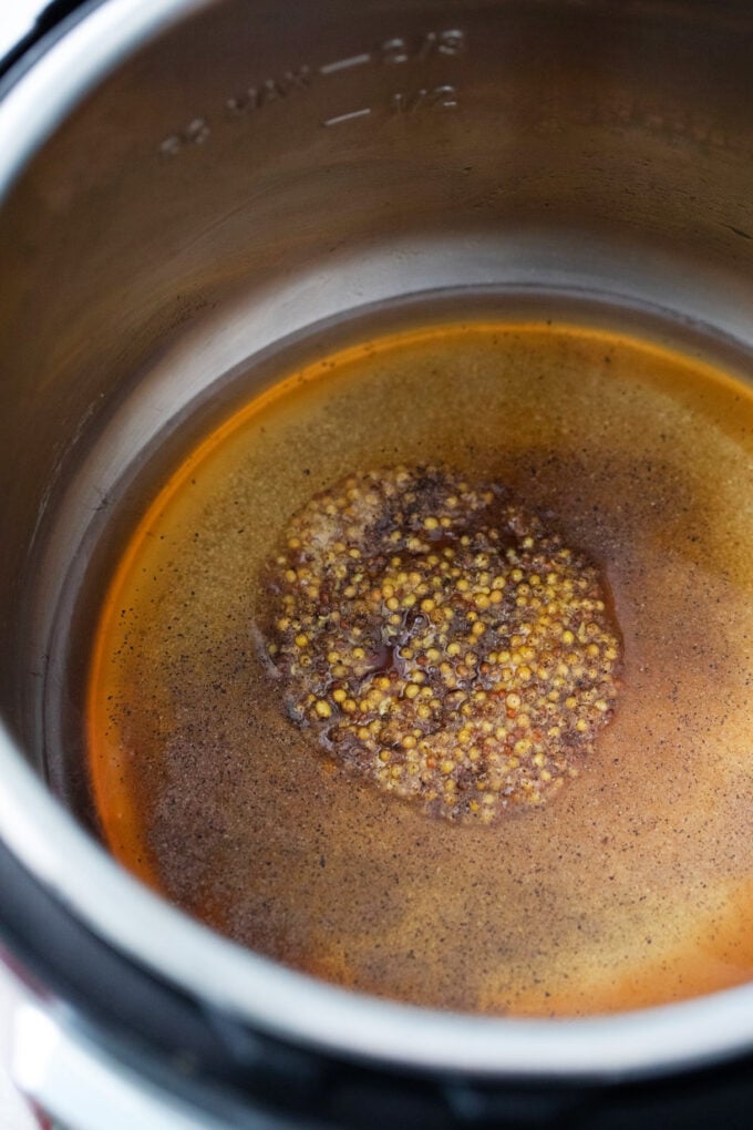 Making Instant Pot apple cider sauce with ground mustard and brown sugar.