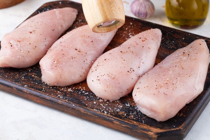 Seasoned chicken breast on a cutting board.