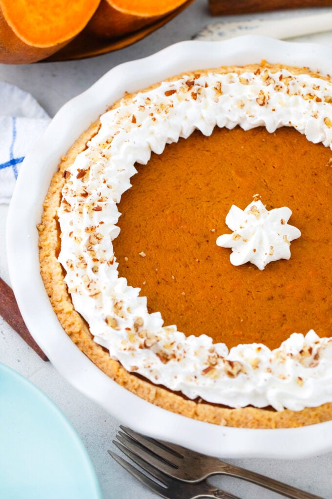 Homemade sweet potato pie garnished with whipped cream and cinnamon.