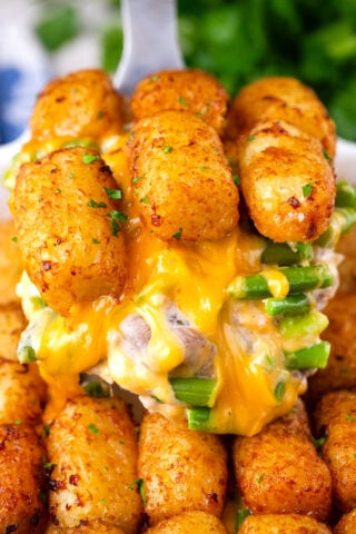 Pulling a slice of very cheesy homemade tater tot casserole.