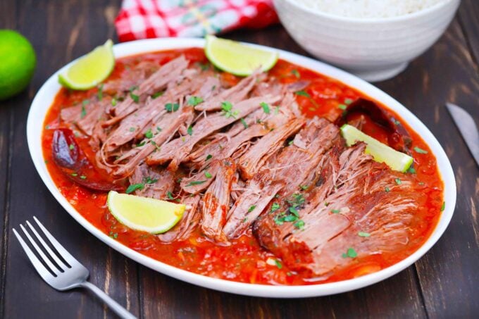 Shredded Mexican pot roast served with lime wedges.