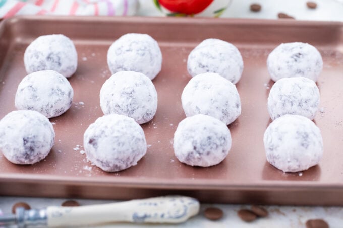 Chocolate crinkle cookie balls on a baking sheet.