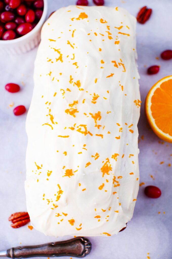 Cranberry bread topped with glaze and orange zest.