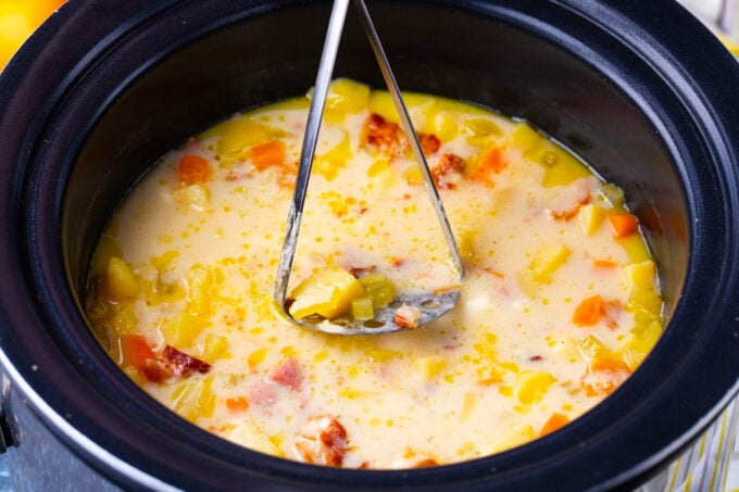 Mashing slow cooker ham and potato soup.