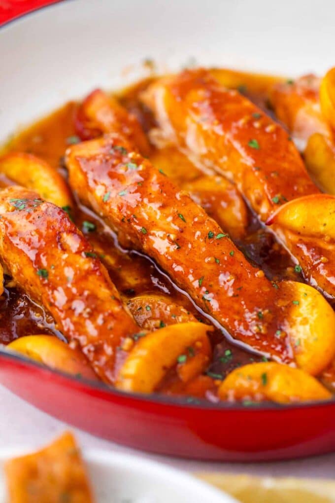 peach salmon in a skillet in a sticky sauce