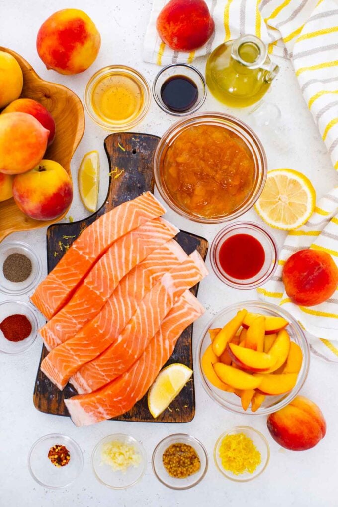 peach salmon ingredients arranged in bowls and fish filets on a cutting board