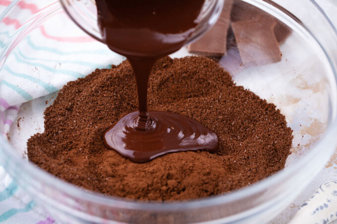 Adding melted chocolate to a bowl of brown sugar.