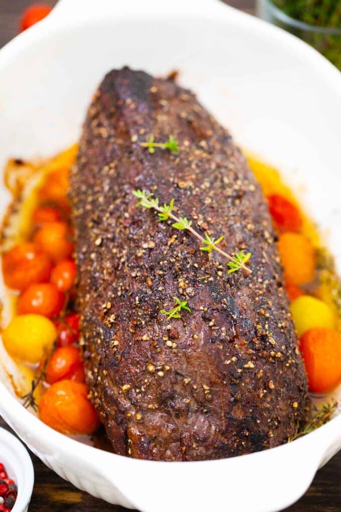 garlic and red wine roasted beef tenderloin in a baking dish with grape tomatoes