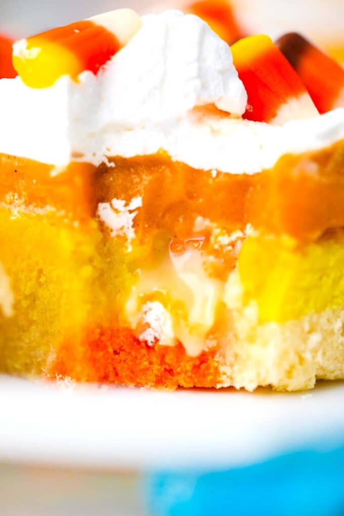 a slice of candy corn poke cake revealing its layers and filling