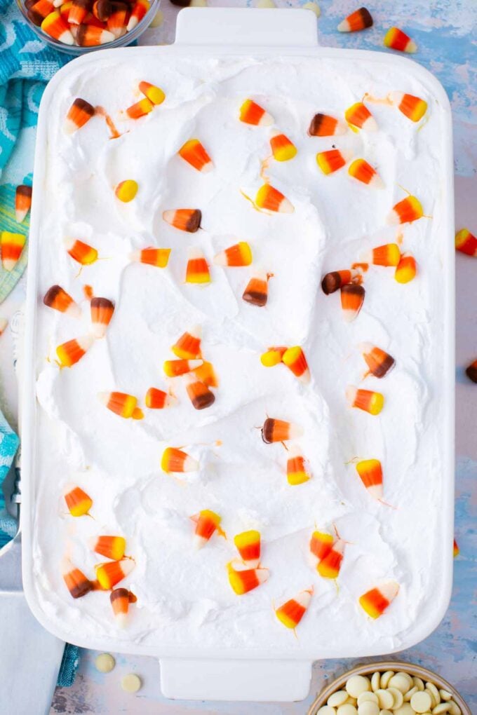 overhead shot of candy corn poke cake with whipped cream and decorated with candy corn