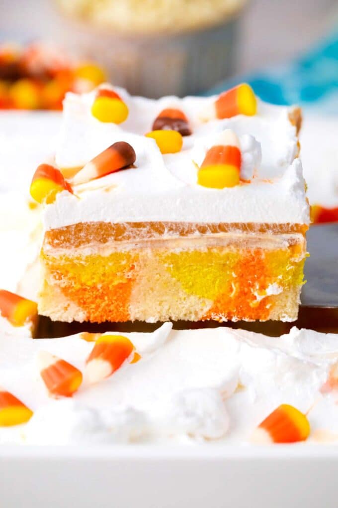 lifting a candy corn poke cake slice on a serving spatula