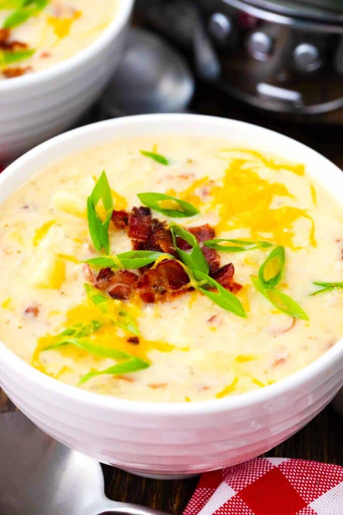 a bowl of slow cooker baked potato soup topped with bacon and cheese