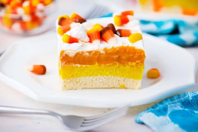 a slice of candy corn poke cake with pumpkin spice pudding layer