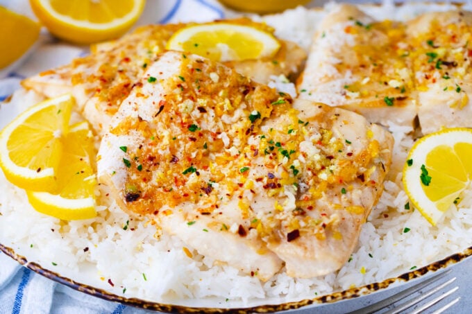 A serving plate with rice and baked lemon garlic tilapia.