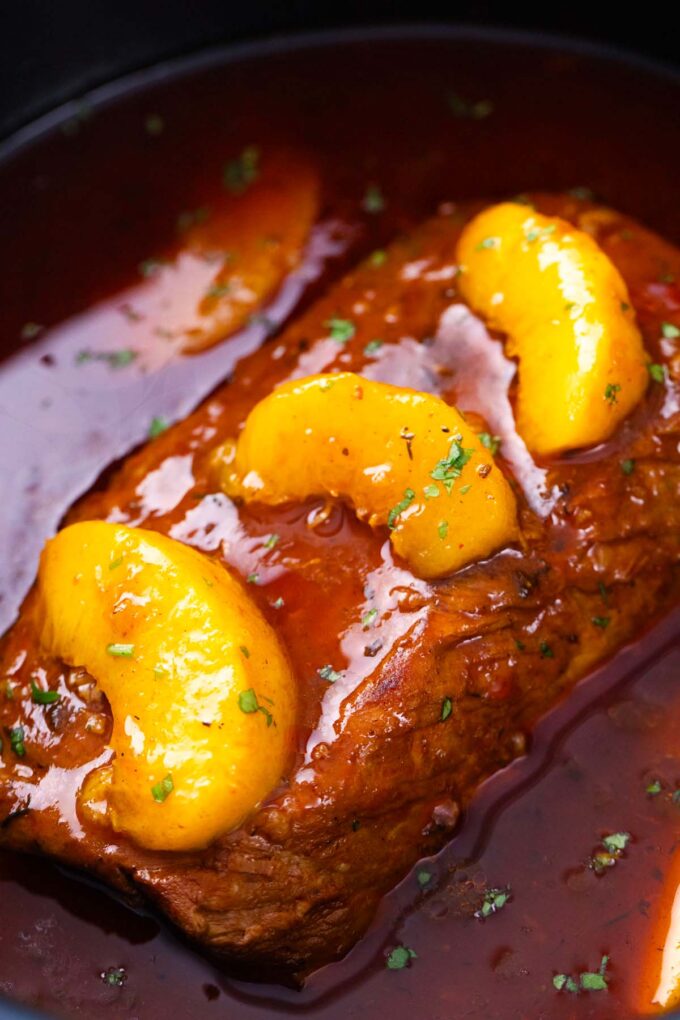 Slow cooker peach pork loin topped with peaches.