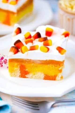 candy corn poke cake with a pumpkin spice pudding layer, whipped cream and candy corn