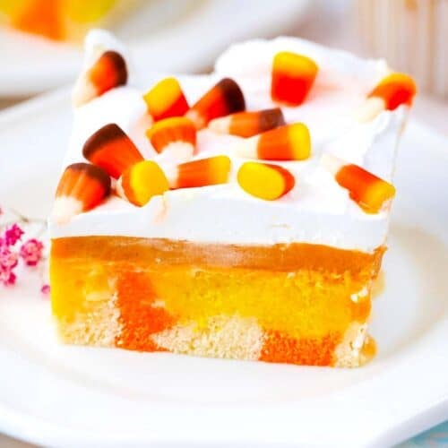 candy corn poke cake with a pumpkin spice pudding layer, whipped cream and candy corn