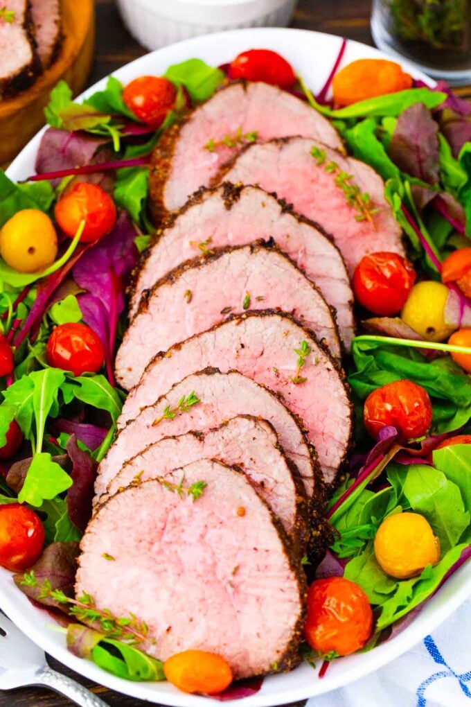 sliced red wine roasted beef tenderloin on salad greens