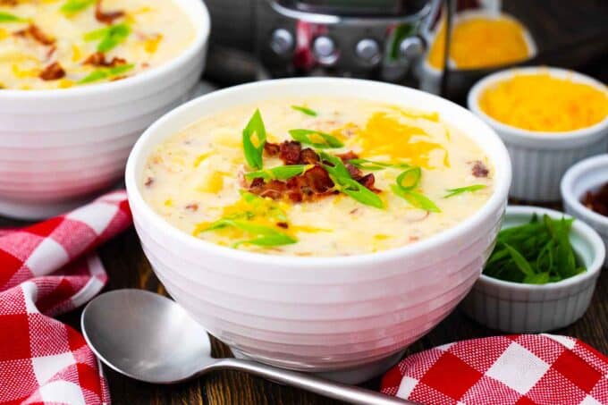 bowls of crockpot baked potato soup with cheese and bacon