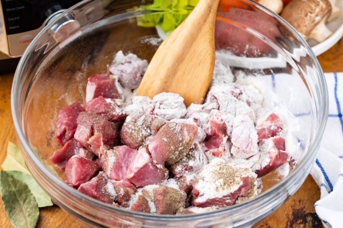 Dredging lamb stew meat in flour.