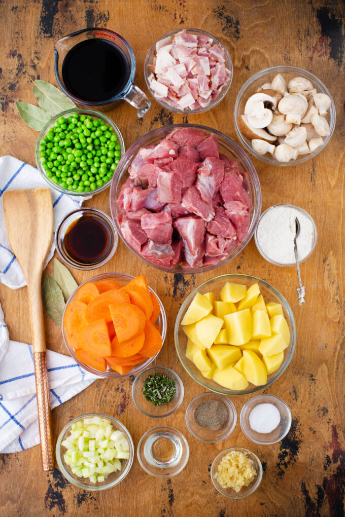 Overhead shot of instant pot lamb stew ingredients in bowls on a wooden surface.