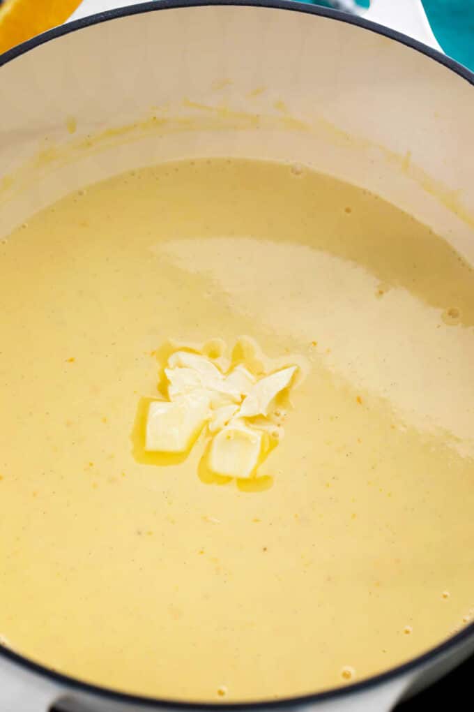 adding butter to orange custard in a saucepan