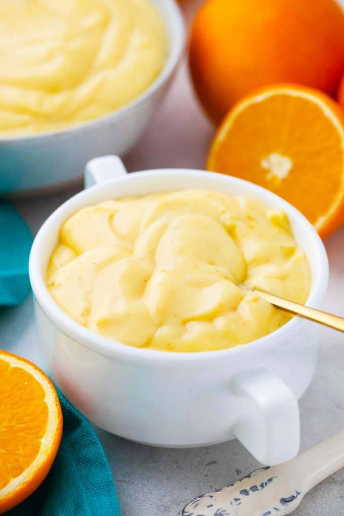 a bowl of homemade orange custard with fresh oranges next to it