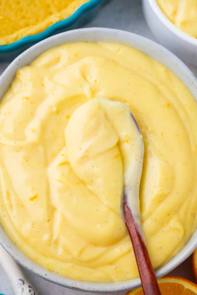 a bowl of creamy orange custard with a wooden spoon in it