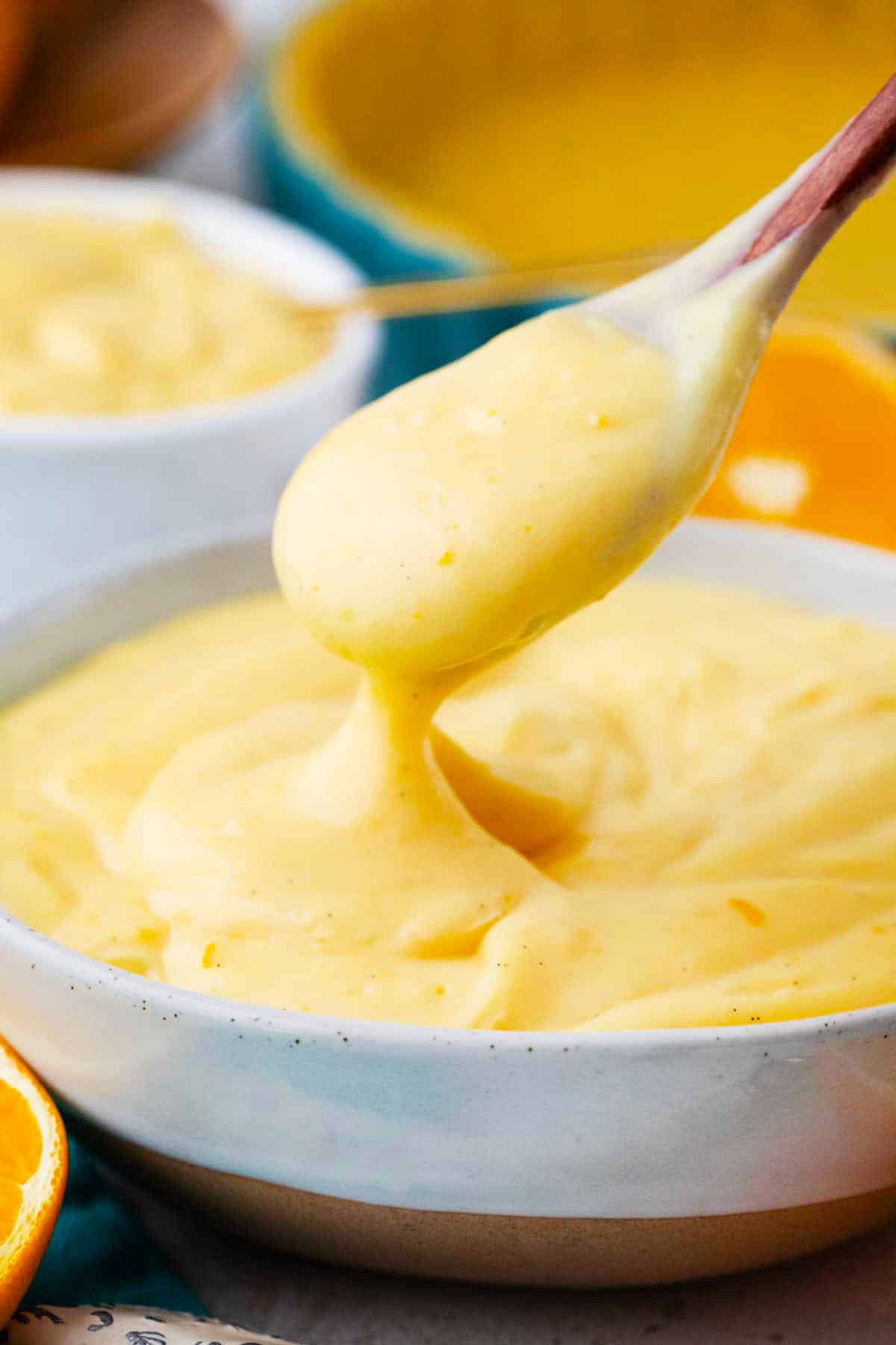 orange custard dripping of a wooden spoon into a bowl