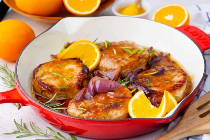 a skillet with orange glazed pork chops