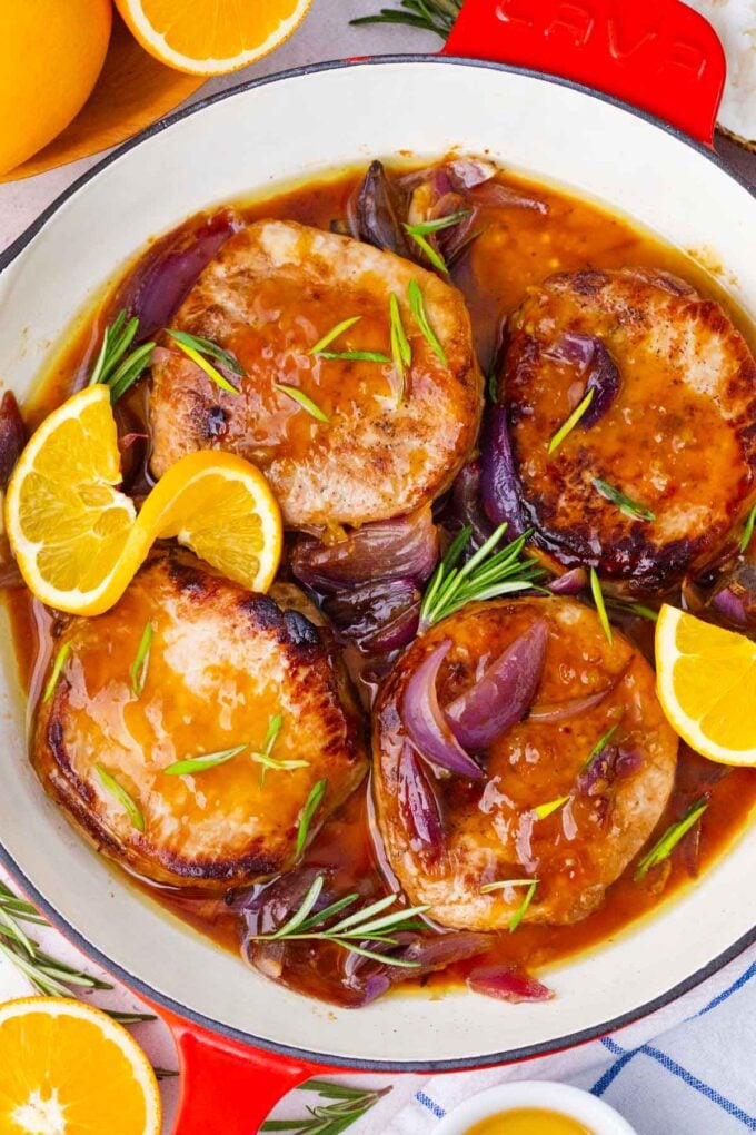 overhead shot of orange glazed pork chops with red onion, rosemary, and orange slices