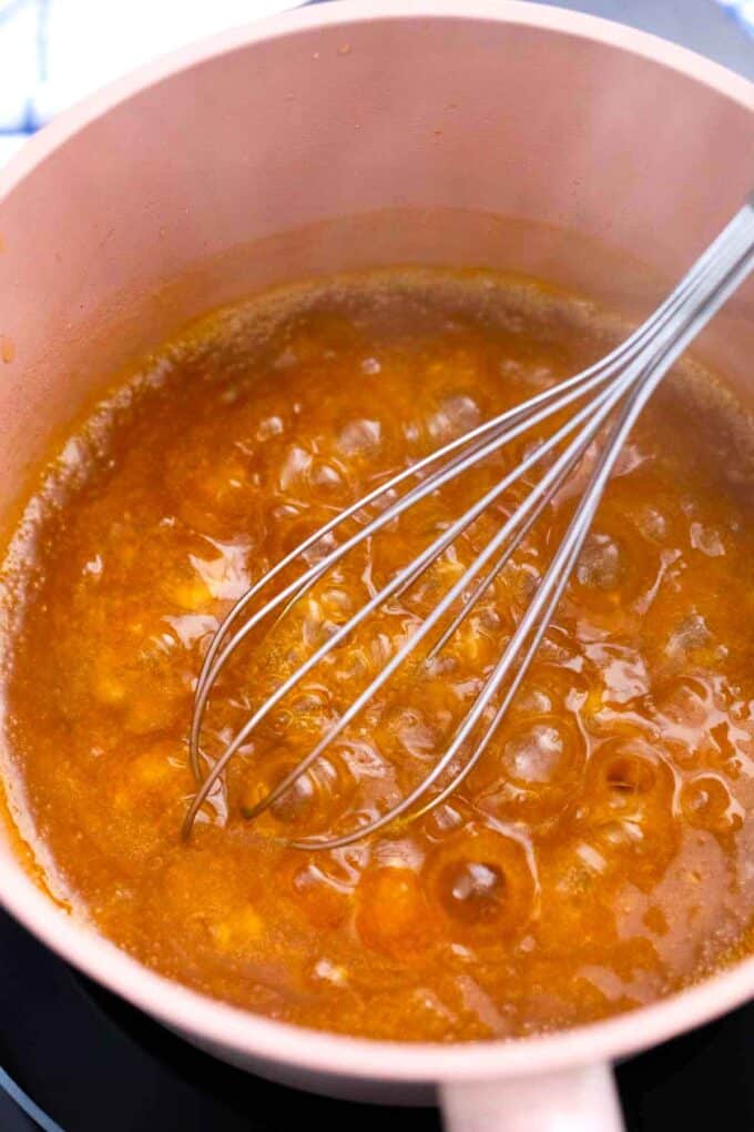 stirring simmering orange sauce in a saucepan