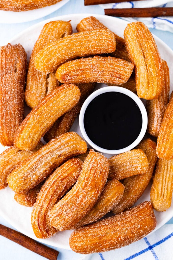 Overhead shot of a plate of homemade churros with chocolate sauce.
