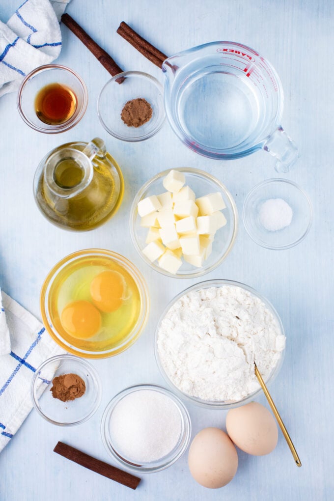 Overhead shot of homemade churros recipe ingredients in bowls on a white surface.