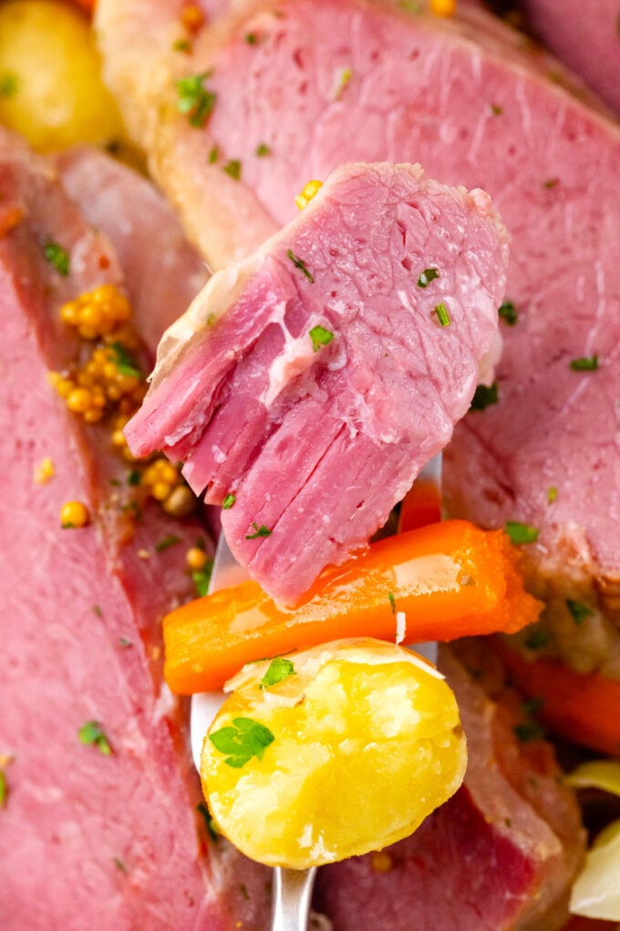 A forkful of very tender crockpot corned beef with a piece of carrot and potato.