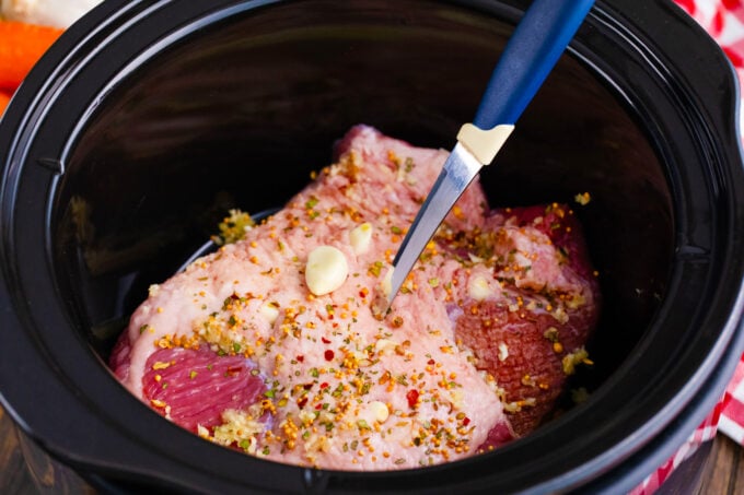 Piercing corned beef to stuff it with garlic cloves.