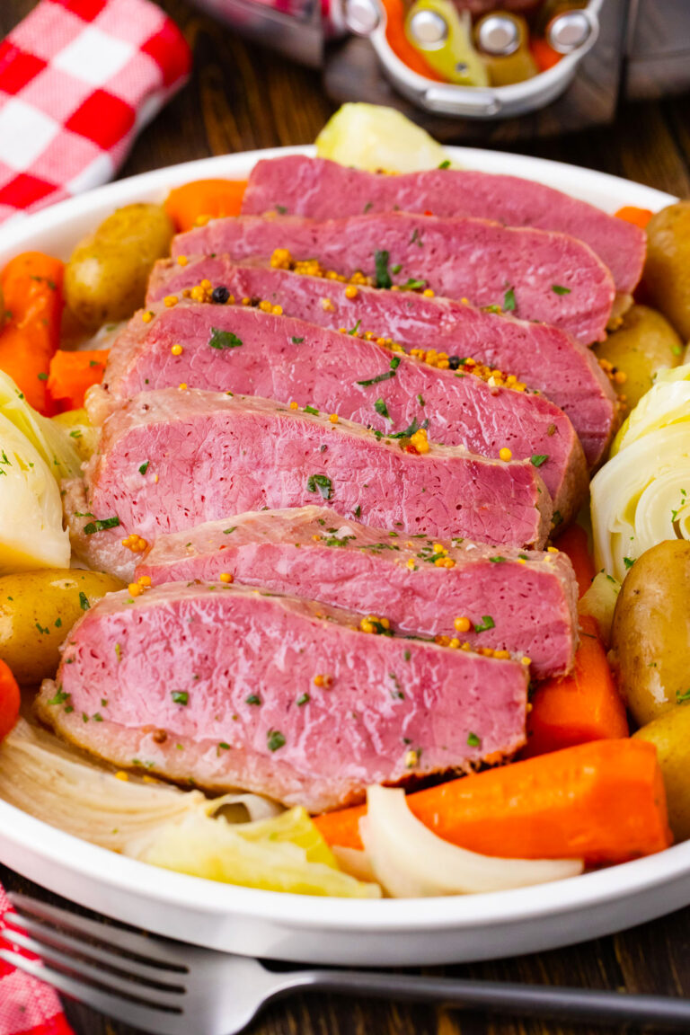 Sliced homemade slow cooker corned beef with carrot, cabbage and potatoes.