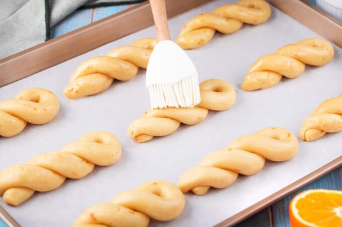Brushing with beaten egg braided Easter Greek Cookies Koulourakia before baking them.