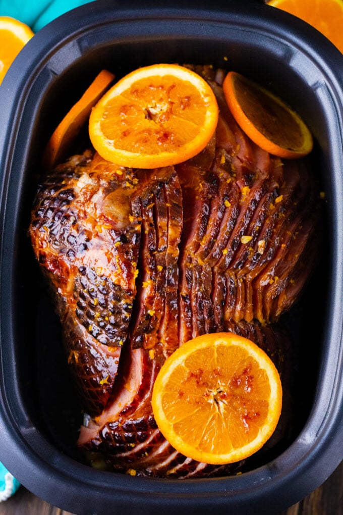 Overhead shot of slow cooker brown sugar ham topped with orange slices.
