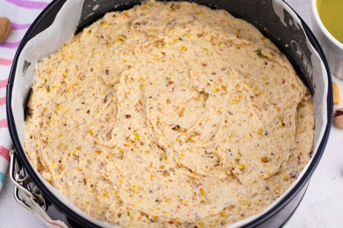 Pistachio coffee cake batter in a springform pan.
