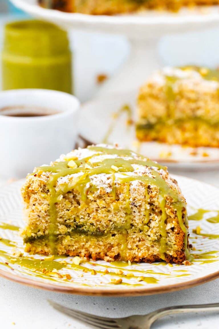 Sliced pistachio coffee cake with pistachio spread layer and topped with pistachio cream.