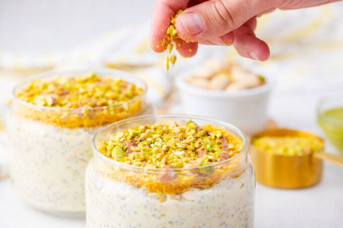 Sprinkling chopped pistachios on Dubai chocolate overnight oats.