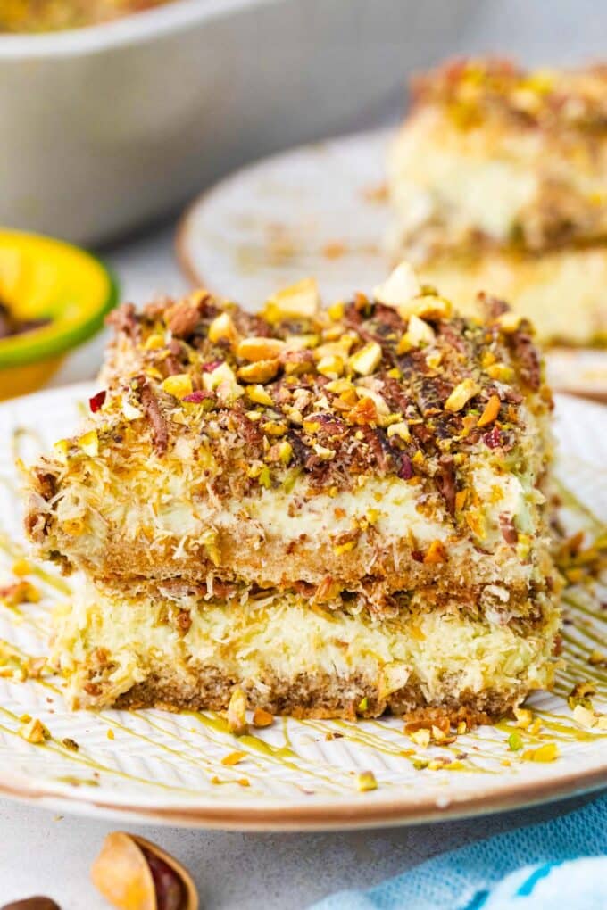 A slice of no bake Dubai chocolate tiramisu topped with chocolate sauce, pistachio sauce, and chopped pistachios.
