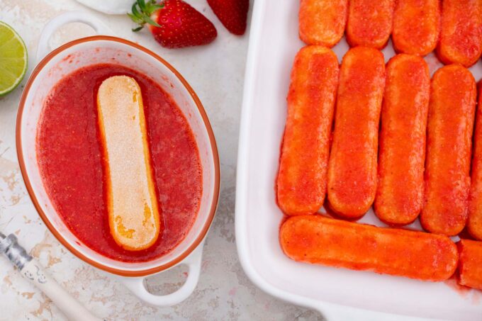 Dipping Savoiardi cookies into tequila strawberry sauce.
