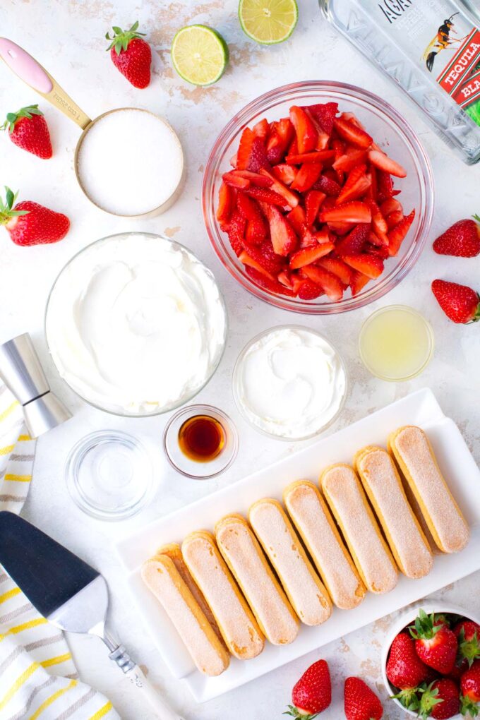 Overhead shot of creamy strawberry margarita tiramisu ingredients in bowls on a table.