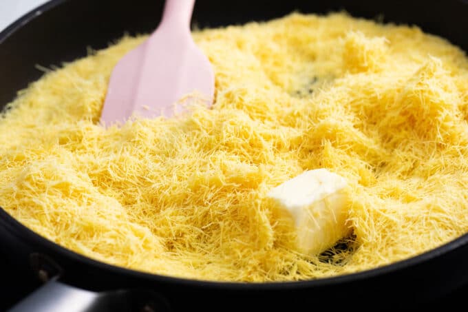 Cooking kataifi dough and butter in a skillet.