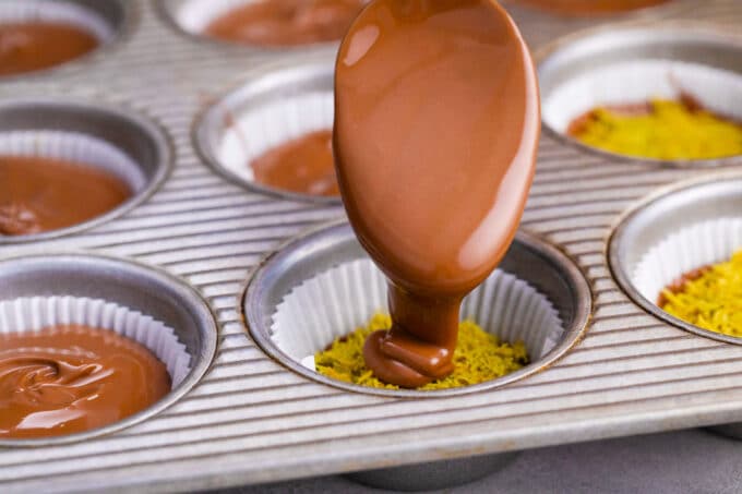 Adding melted chocolate on top of Dubai chocolate pistachio cups.