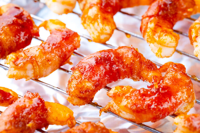 Glossy bacon wrapped shrimp with brown sugar on a wire rack.