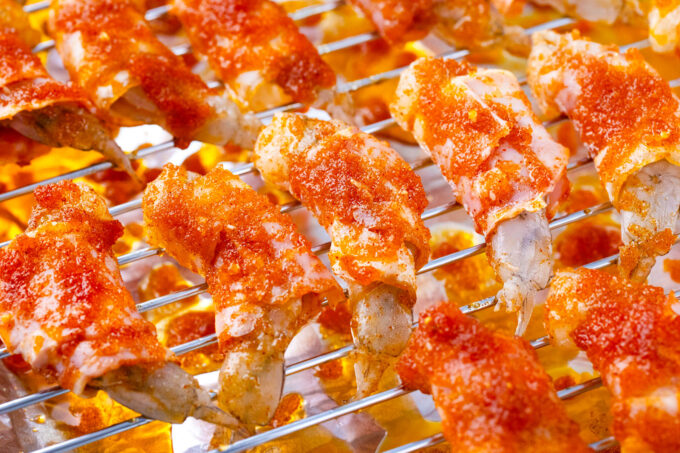 Bacon wrapped shrimp with brown sugar on a wire rack before it goes into the oven.